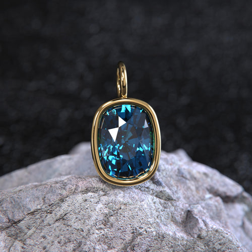 May include: A gold pendant with a large, faceted, blue gemstone. The pendant is set in a gold bezel and has a simple, elegant design.
